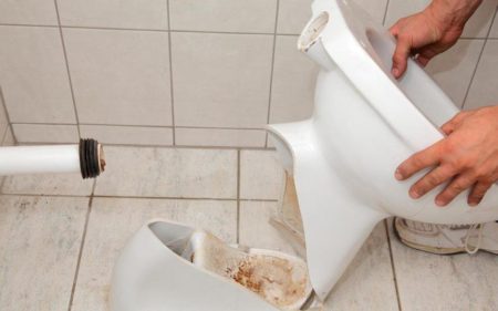 Man's hand while holding broken toilet